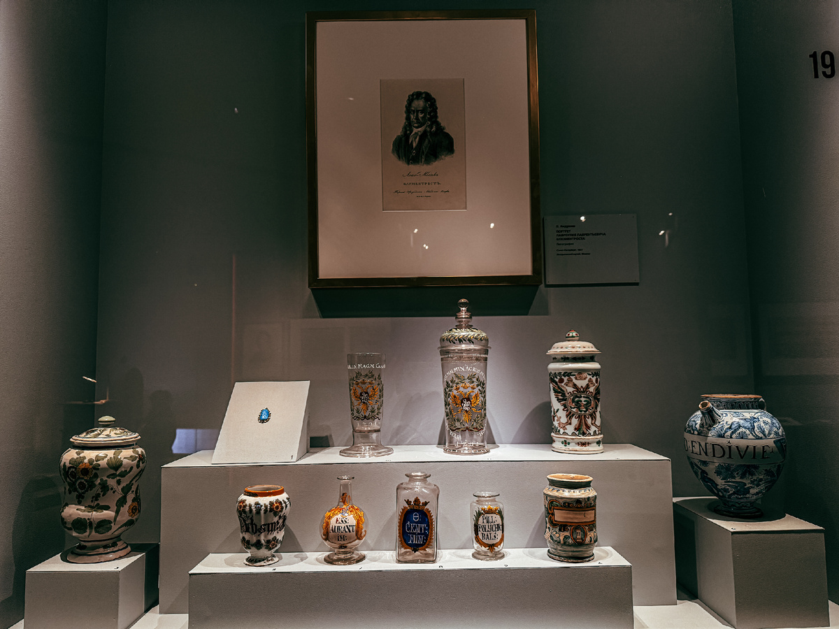 Аптекарская посуда, заказанная Петром I. В центре потртрет Л.Л. Блюментроста. Выставка «Последний триумф Петра Великого. Впереди вечность».