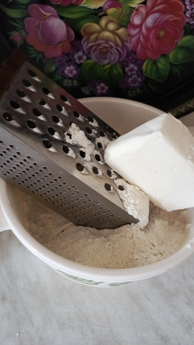 Натереть охлаждённое сливочное масло на тёрке, подсыпая муку на тёрку.  Фото автора.