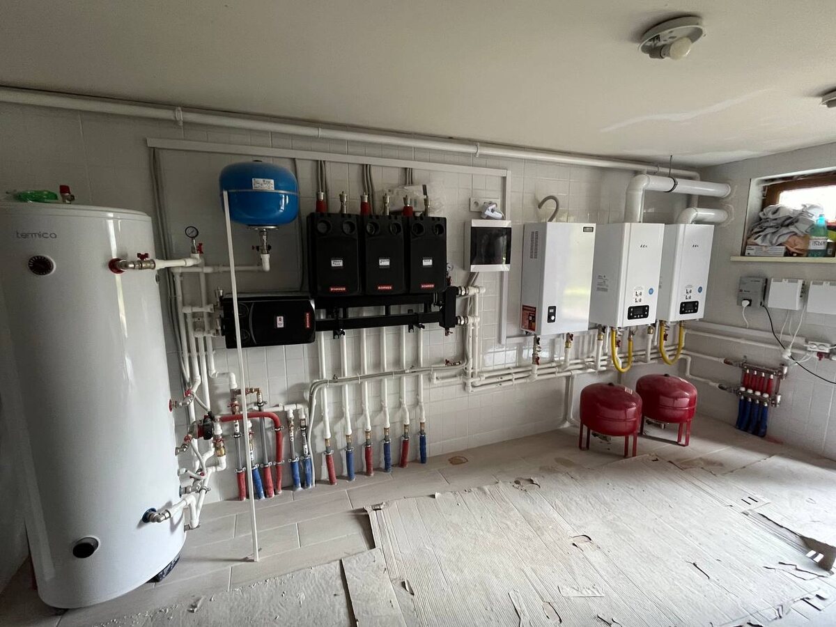 Пример компактной котельной: настенный газовый котёл, насосные группы и бойлер для горячей воды установлены в отдельном помещении загородного дома. Такая котельная позволяет разместить всё оборудование аккуратно и безопасно, вне жилых комнат. При проектировании важно предусмотреть достаточно места для всех узлов и удобного доступа к ним для обслуживания.