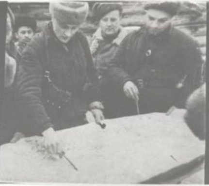 Кадр из фильма «Народные мстители» 1943 г. Совещание в д. Ровняк Порховского района 13 февраля 43 г. Пенкин в белом полушубке стоит за левым плечом Германа. Справа – еще один чкаловец, начштаба 3-ей ЛПБ Иван Васильевич Крылов.