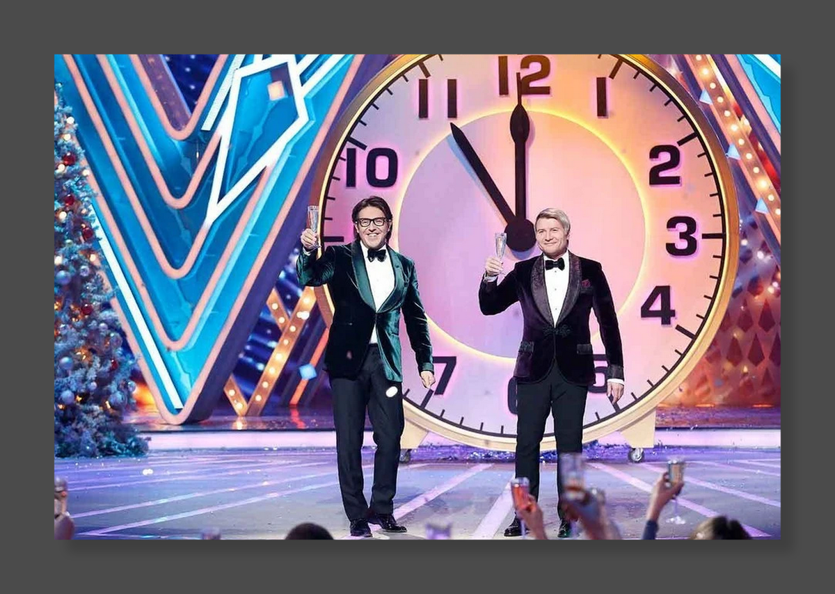 Николай Басков с начала 2000-х не просто поет на «Новогоднем огоньке», он «хозяйничает» в студии. 9-й год подряд среди ведущих и Андрей Малахов. Стоп-кадр трансляции