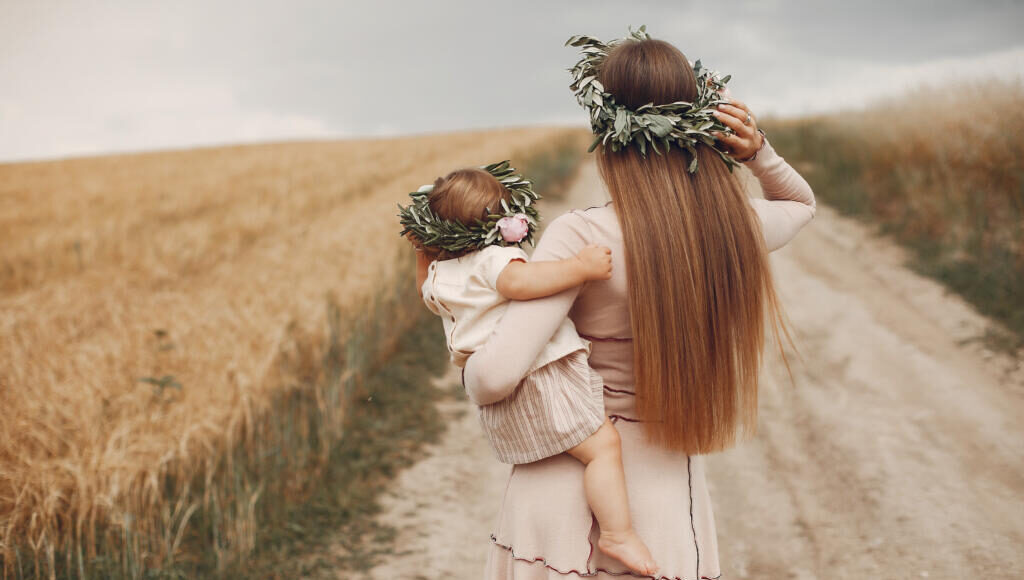    Family in a summer field. Mother in a wbrown dress. Cute little girl in a wreath Журналист