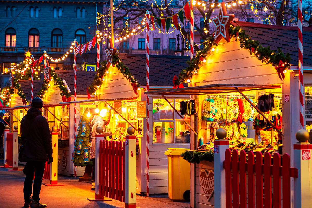 Уютные домики-ярмарки заполняют центр Петербурга мягким светом и ароматом горячей выпечки. Здесь продают тёплые варежки, сувениры и уличную еду. Фото: Lizavetta / Shutterstock / Fotodom