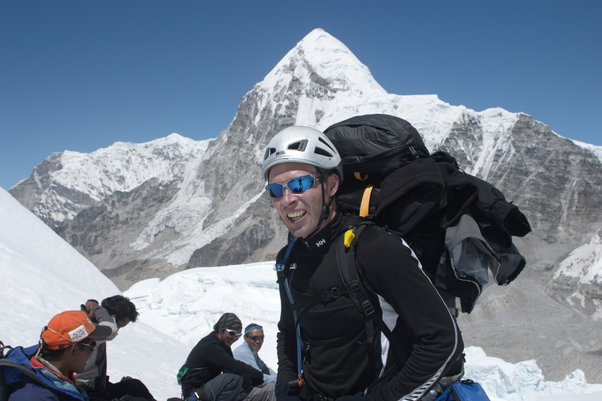 Фергюс Уайт на ледопаде на высоте 5700 метров. На нем только жилет с длинными рукавами. Позади несколько шерпов отдыхают, наслаждаясь утренним солнцем. На них нет ни перчаток, ни тёплых шапок. (Фото: Анхель Эсекьель Арместо)