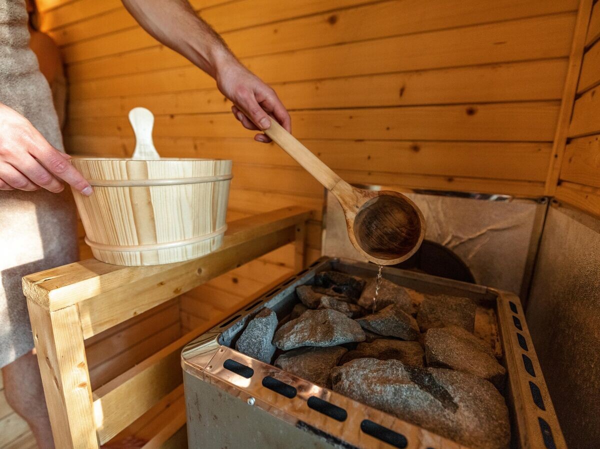    Мужчина наливает воду на камни в бане | © iStock.com / AzmanJaka