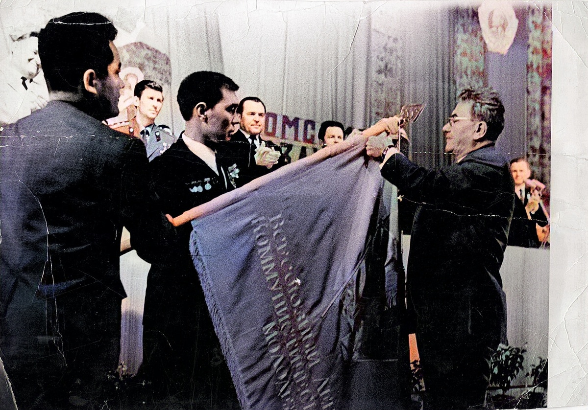 Д. А. Кунаев прикалывает знак награды к знамени ЛКСМ.