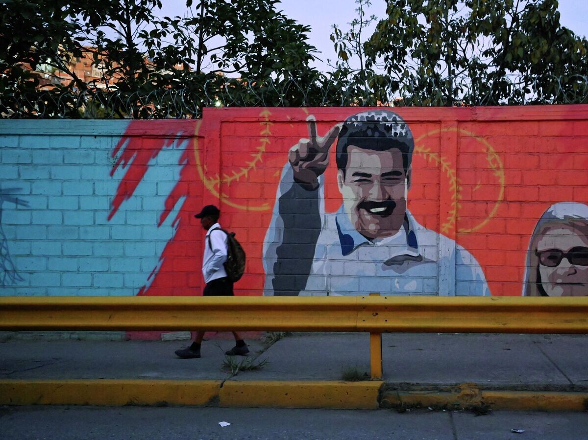    Мужчина проходит мимо изображения президента Венесуэлы Николаса Мадуро и его жены Силии Флорес в Каракасе | © REUTERS / Maxwell Briceno