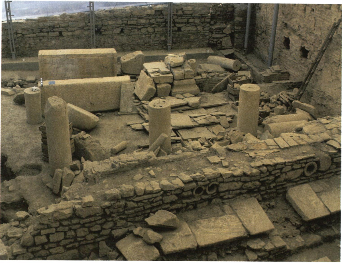 Вид из помещения WT 1 в помещение WT 2 комплекса Хангхауз 2 в Эфесе во время археологической кампании 2006 года.

Стена на переднем плане разделяет два помещения. За тремя стоящими колоннами различимы элементы камнерезной машины. Слева (с запада) направо (на восток) видны: два мраморных блока со следами распиловки (длина ближнего блока — 2,6 м), каменная кладка из крупных вторично использованных блоков, служившая западной опорой балок вала, канал для водяного колеса и отводящий канал для сброса отработанной воды (оба расположены в полу помещения). В восточной стене заметны два крупных гнезда для балок — второй опоры балок вала, а в верхней части стены находится прорезь для подачи воды из верхнего водовода.