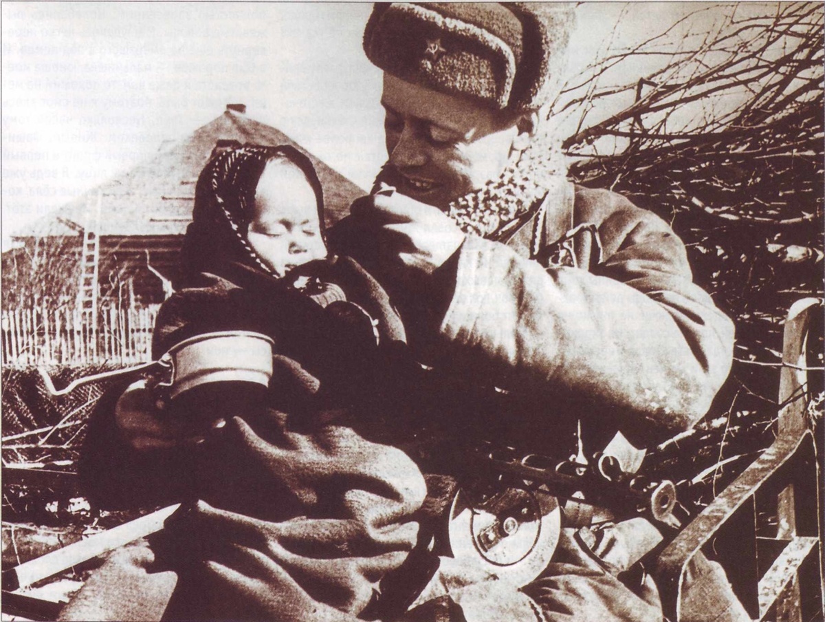     Старший сержант Е. Моисеев кормит найденную им девочку Валю. / Е. Кинеловский / из архива журнала "Родина"