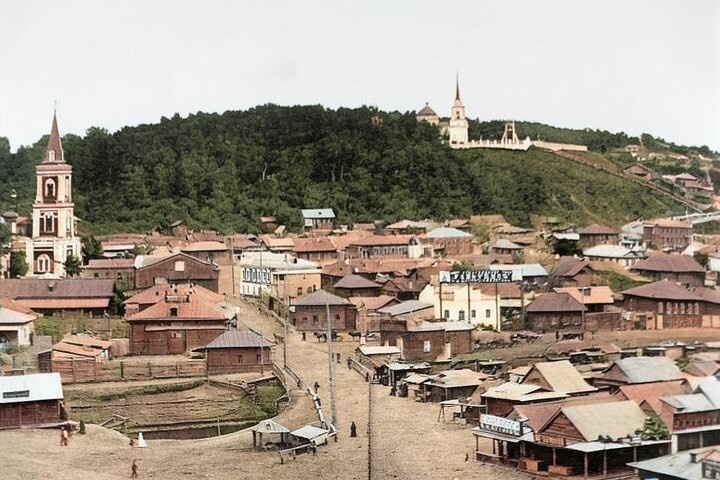 Барнаул. Век XIX. Приземистый деревянный городок, грунтовая дорога, густой лес, взбирающийся на гору. Ввысь устремлены только шпили церковных колоколен (по книге "Барнаул" Администрация Барнаула) (восстановлено с помощью ИИ).