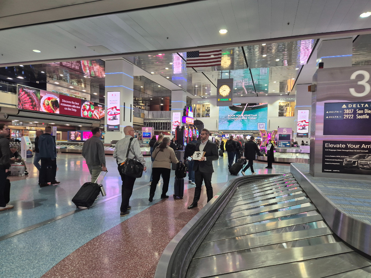 прибывших на выставку пассажиров встречающие ловят у багажных лент, аэропорт, Лас-Вегас 