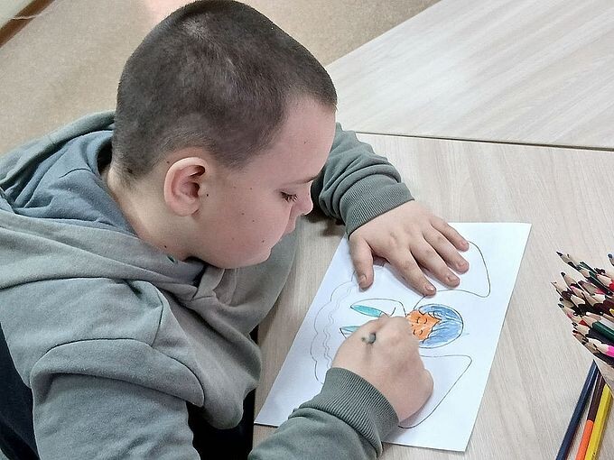 Мальчик рисует карандашом фигуру ангела