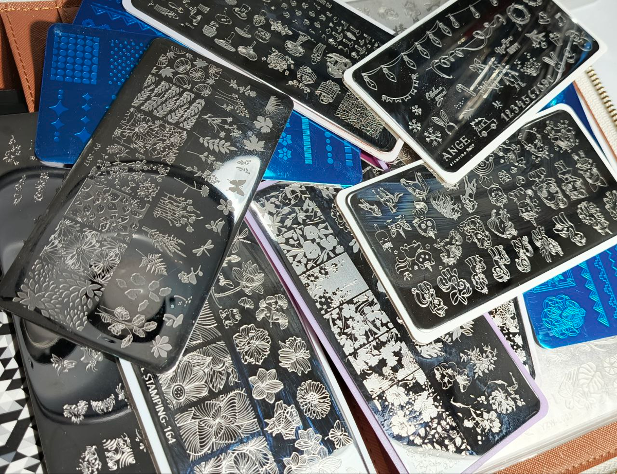  Специальный стемпинг-лак
У него высокая пигментация и нужная плотность. Обычные лаки и гель-краски либо прозрачные, либо слишком быстро схватываются — рисунок не переносится.
2️⃣ Гравировка пластины
Глубокая и чёткая гравировка удерживает краску.
Если гравировка слабая, рисунок не наберётся даже самым липким штампом и самой пигментированной краской — здесь техника уже не спасает.
3️⃣ Количество краски
Избыток краски заливает линии, недостаток — не заполняет гравировку.
Важно, чтобы рисунок был заполнен полностью, но без «луж».
4️⃣ Работа скрапером
Угол примерно 45°, одно уверенное движение. Сильное давление вычищает краску из гравировки — и штампу нечего забирать.
5️⃣ Скорость работы
Стемпинг не любит пауз. Пока думаешь, лак подсыхает, и перенос уже будет неполным.
6️⃣ Нажим штампом
Не давим сверху. Используем лёгкий перекатывающий контакт, чтобы не смазать линии и сохранить чёткость рисунка.
7️⃣ Штамп и его липкость
Штамп важно подбирать по липкости. Слишком липкий тянет и смазывает рисунок, недостаточно липкий — не берёт краску.
Очищаем штамп только липкой лентой или роликом, без жидкостей.
8️⃣ Подготовка ногтя
Поверхность должна быть ровной и хорошо обезжиренной. Если ноготь жирный или с липким слоем, рисунок может поплыть при переносе или перекрытии.