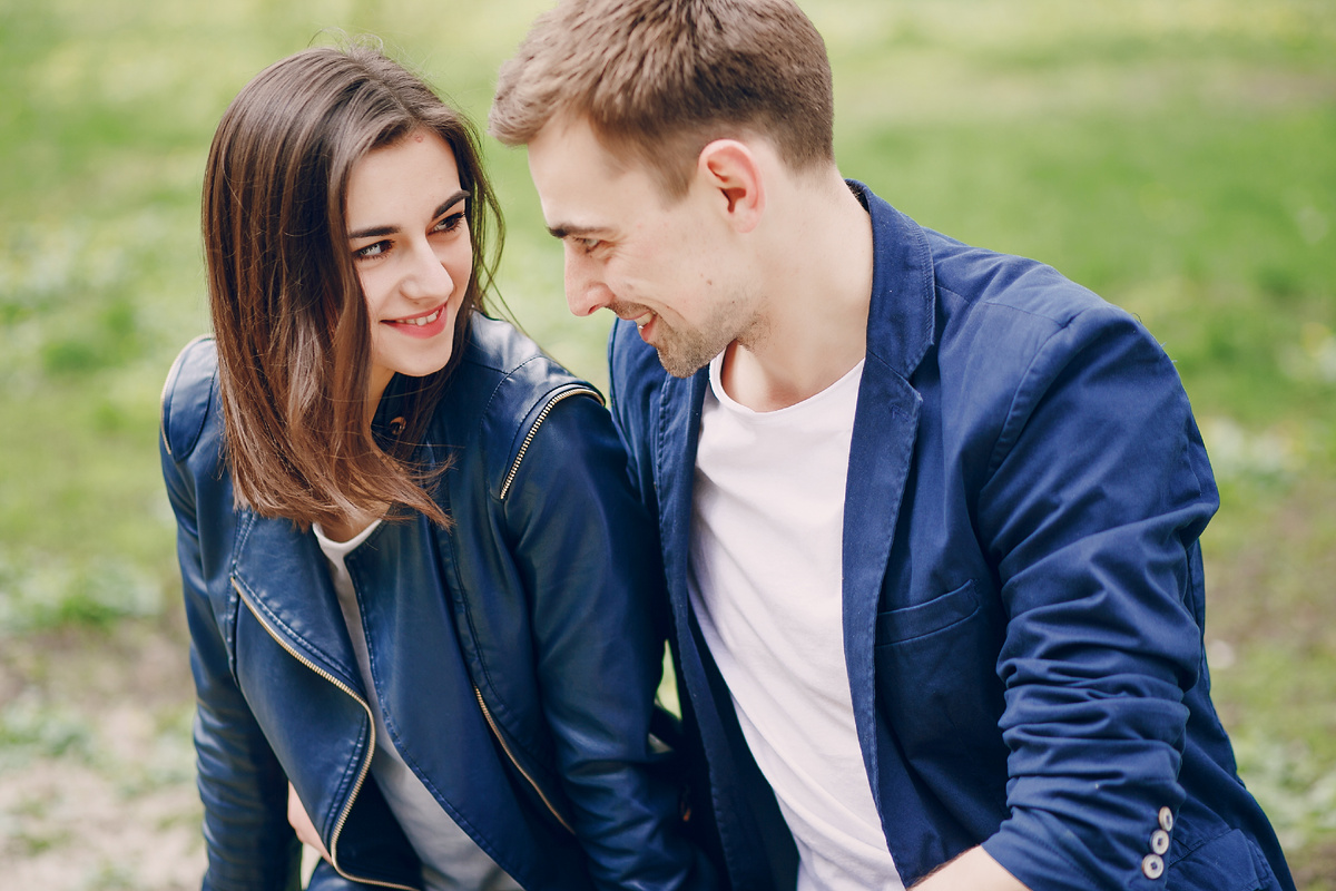 Пара на прогулке в парке: девушка и парень смотрят друг на друга и улыбаются — про взаимопонимание и умение слышать просьбы
