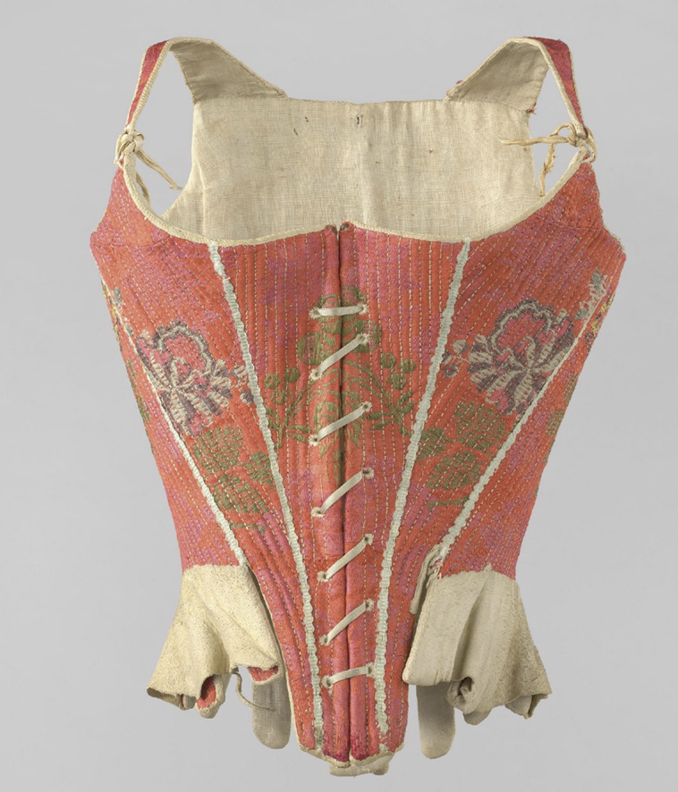 Корсет, обтянутый вишнево-красной шерстяной тканью, украшенный полихромными цветами и белой тесьмой вдоль пяти швов на спине и четырех швов спереди. 
По всей длине вшиты деревянные косточки. Спереди по центру – отверстия для шнуровки и заостренный вырез, сзади – шесть застежек. В боках – удлинители из морской кожи.
