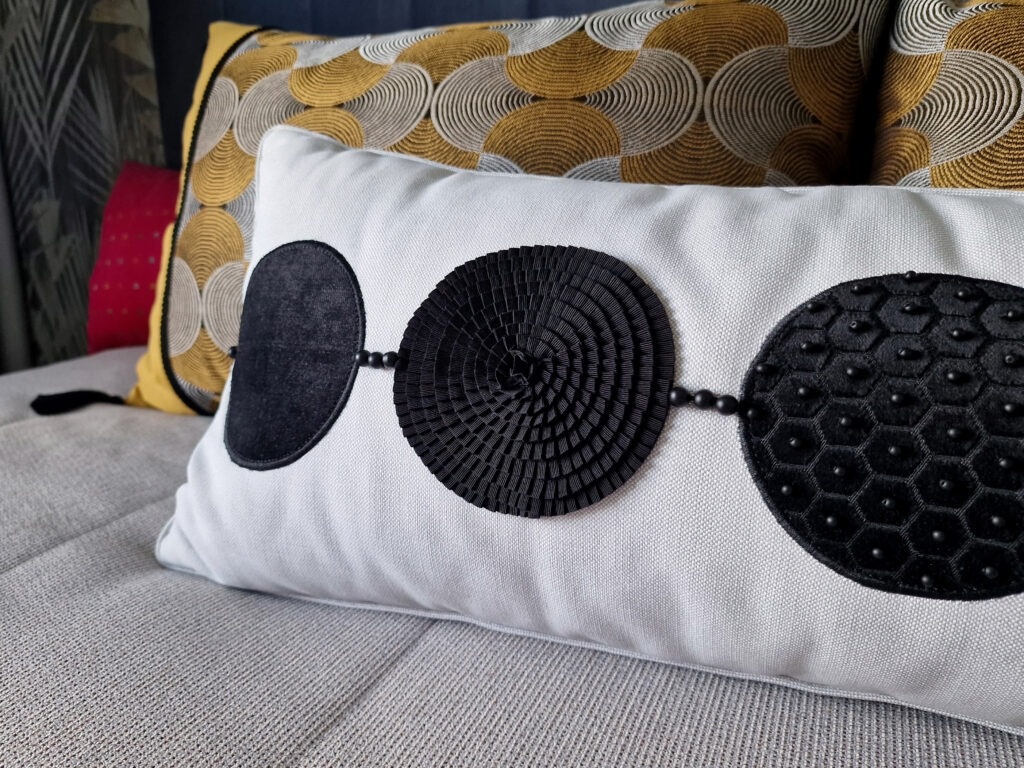 Подушка «Агатовые бусы». В основе каждой «бусины» орнамента различные фактуры чёрного бархата и тесьма-плиссе. Некоторые элементы вручную расшиты натуральными агатами. Проект «Зебровое манто», ЖК «Петр Великий», СПб