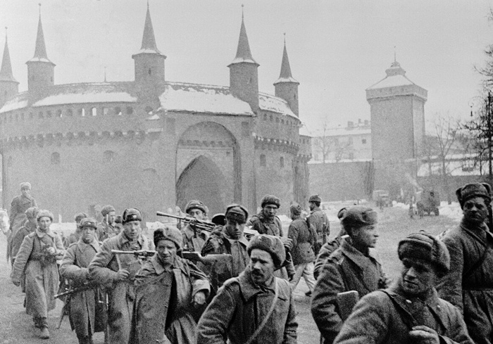 Колонна красноармейцев проходит мимо оборонительного бастиона Барбакан в освобождённом Кракове. 