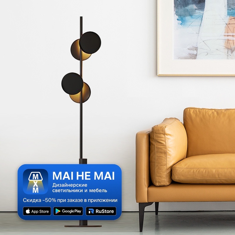 Черный напольный торшер с круглыми плафонами рядом с диваном в современной гостиной с нейтральными стенами и акцентным освещением