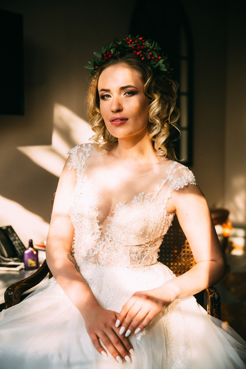 Невеста в кружевном платье стоит в лучах закатного солнца