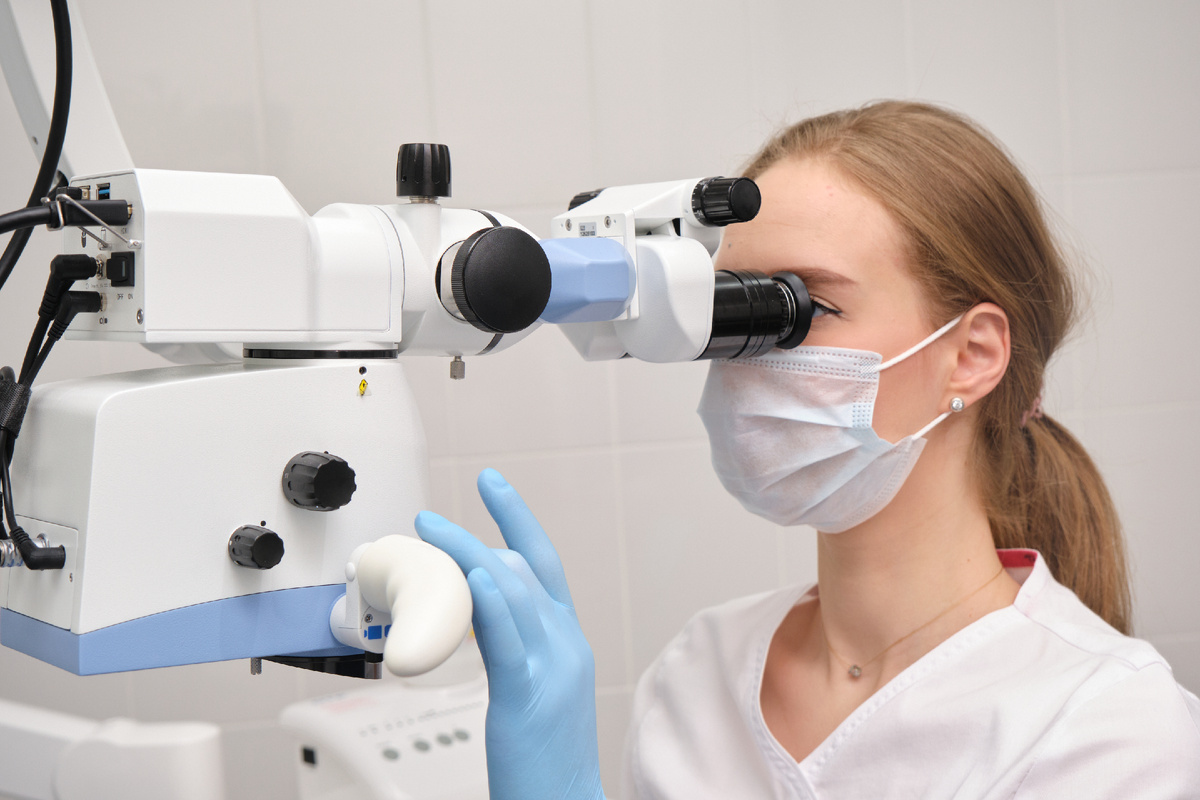 Стоматолог-терапевт проводит лечение с помощью микроскопа