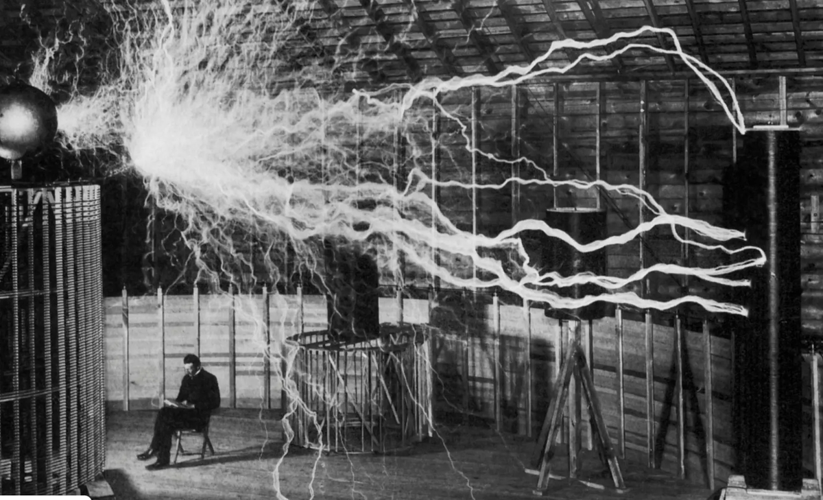 Изобретатель и учёный Никола Тесла в своей лаборатории, где его генератор высокого напряжения с увеличительным передатчиком вырабатывает электрические разряды.