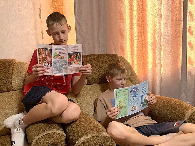 Два мальчика на диване читают буклеты