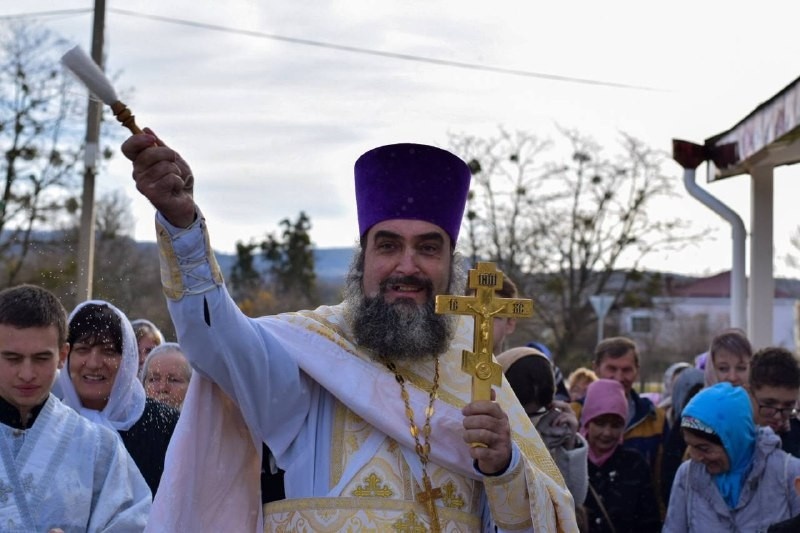 Отец Александр окропляет святой водой прихожан.