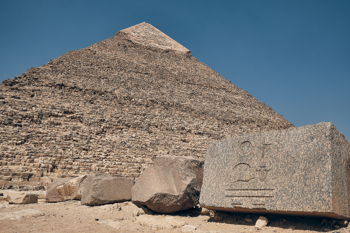 Вид снизу на пирамиду Хефрена и древнеегипетские иероглифы, высеченные на гранитном блоке. Гиза, Большой Каир, Египет. Источник: Shutterstock