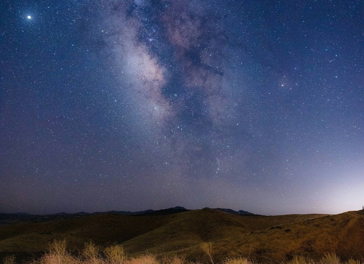 Млечный Путь пересекает небо в виде широкой размытой полосы света. Фото: Jason Leung / Unsplash
