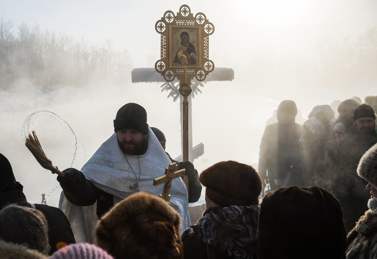     Священнослужитель освящает верующих на территории Ачаирского женского монастыря Честного Креста Господня в Омской области во время празднования Крещения / РИА Новости / Алексей Мальгавко
