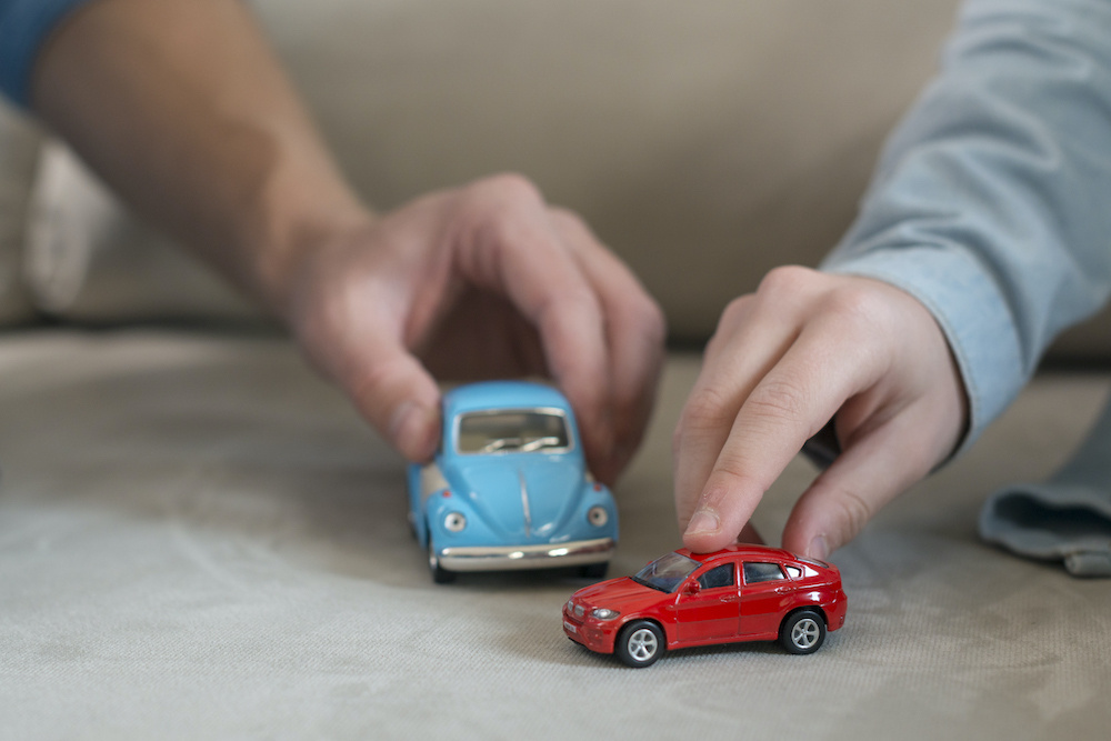 Дети играют в машинки на ковре.