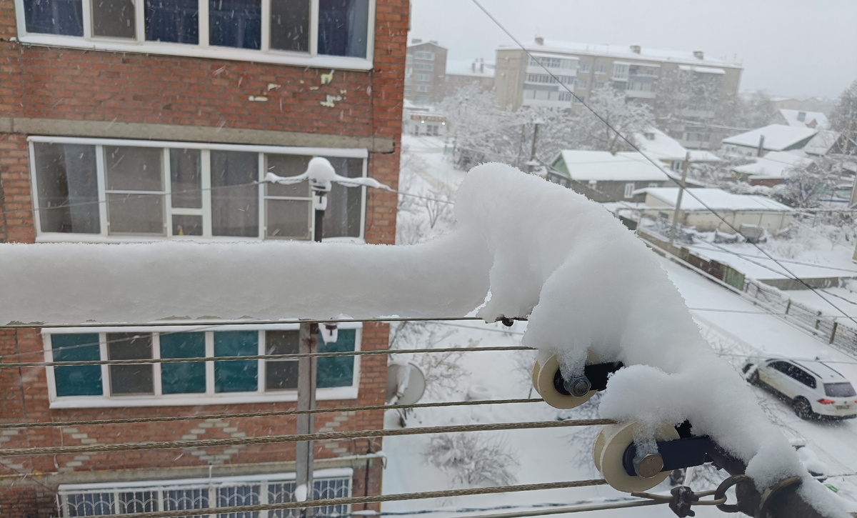 Слой снега на верёвке (трубе) для сушки белья