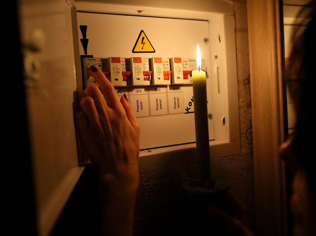   Девушка у электрического щитка в своей квартире во время тестового отключения электричества в Киеве© РИА Новости . Стрингер