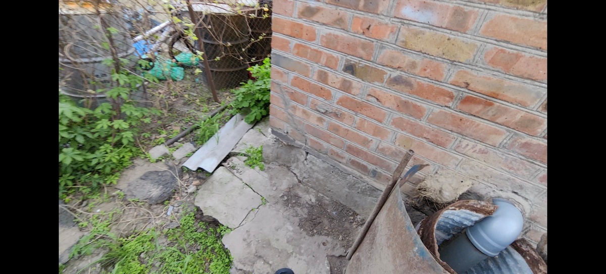 Это стопкадр из видео. Здесь как раз видно угол дома, который просел. И вымытый водой участок под отмосткой. 