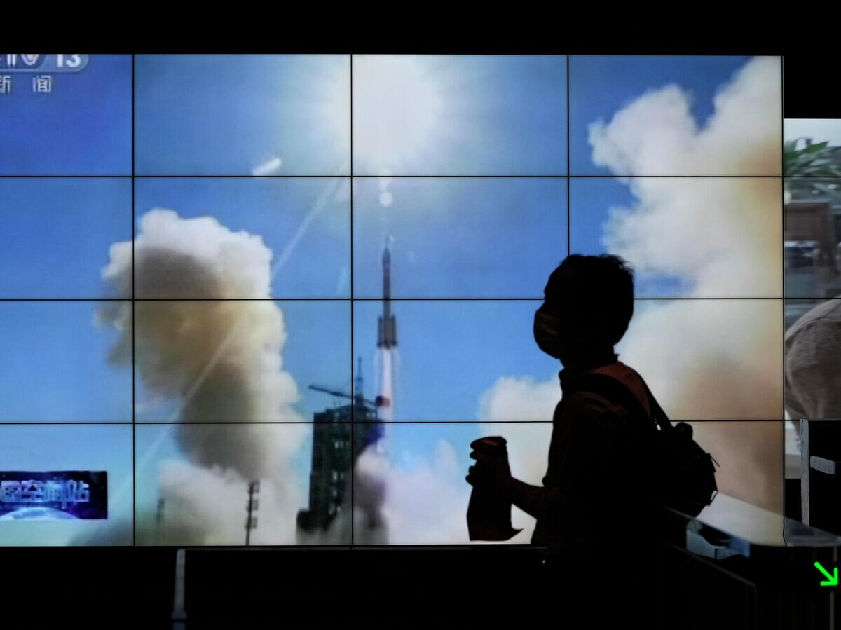    Силуэт мужчины на фоне трансляции запуска ракеты, Пекин | © AP Photo / Andy Wong