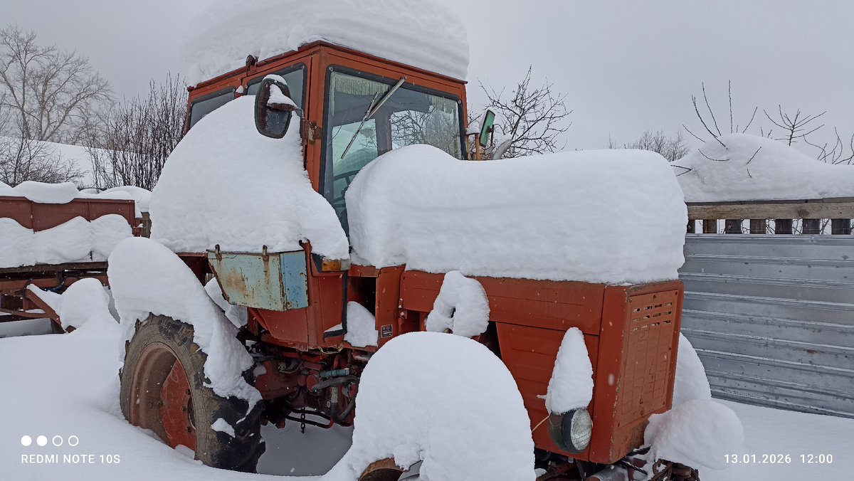 Толстый слой снега на тракторе во дворе. Фото автора.