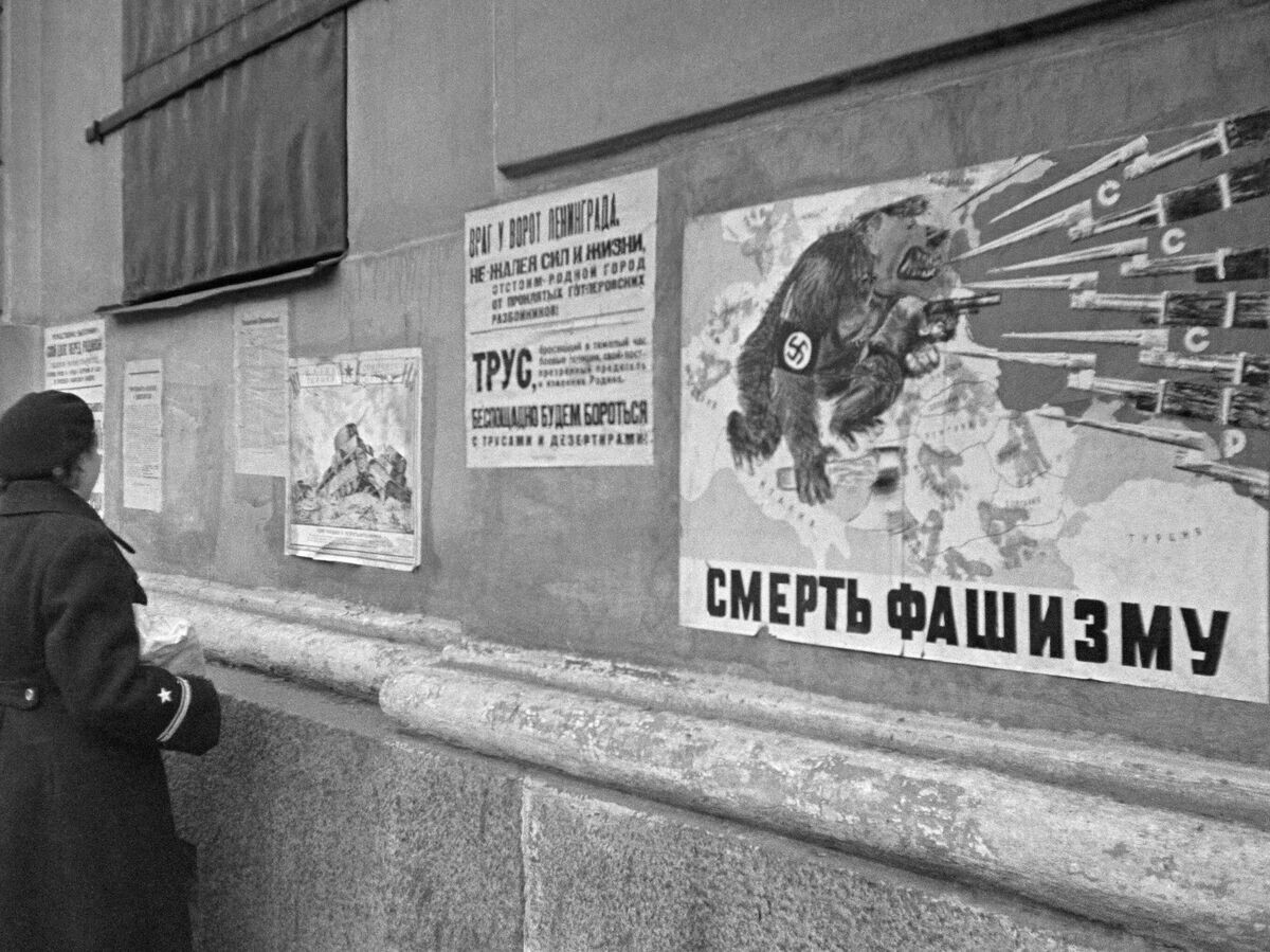    Военнослужащие Балтийского флота у плакатов "Окна ТАСС" на стене здания в блокадном Ленинграде | © РИА Новости / Анатолий Гаранин