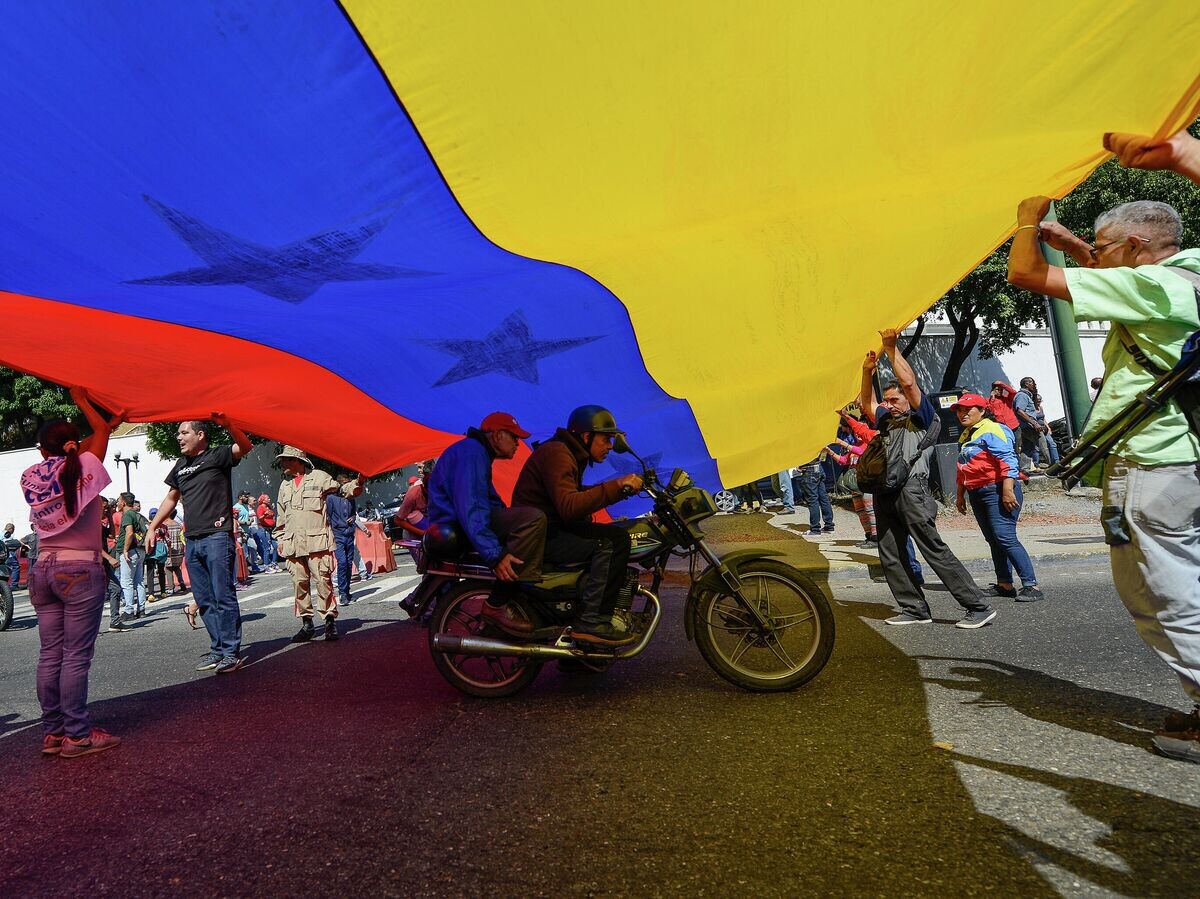    Люди с флагом Венесуэлы в Каракасе | © AP Photo / Matias Delacroix