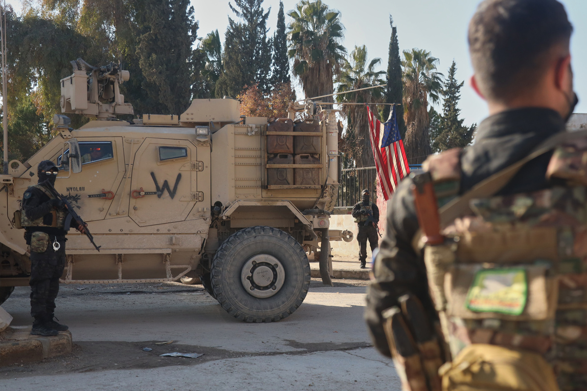     Fighters with the Syrian Democratic Forces (SDF) stand guard near a U.S. military vehicle from the U.S.-led coalition against the Islamic State group in Deir Hafer, Syria, Friday, Jan. 16, 2026 / AP / Baderkhan Ahmad