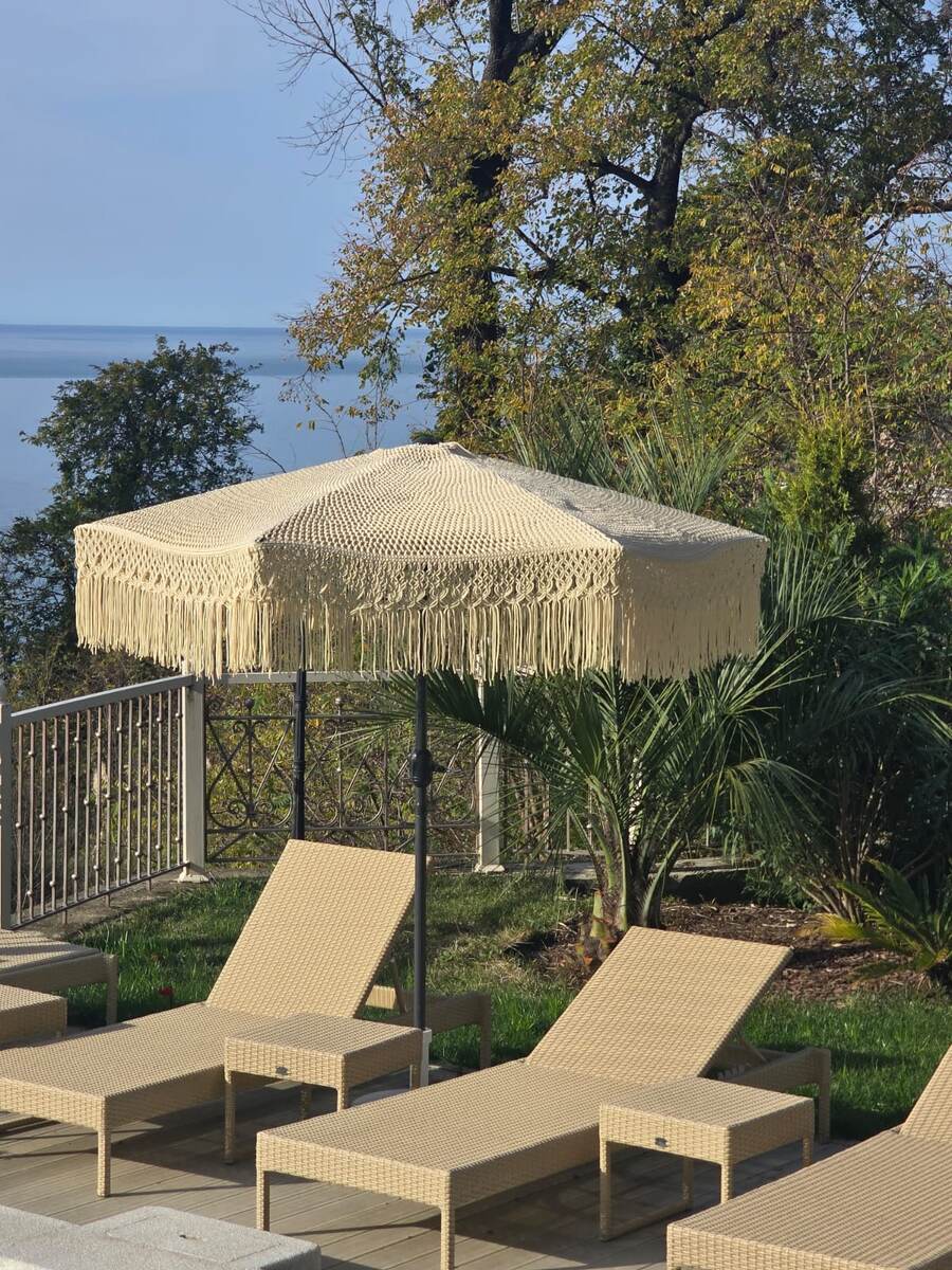 Шезлонги из искусственного ротанга  под шикарным плетеным зонтом.
