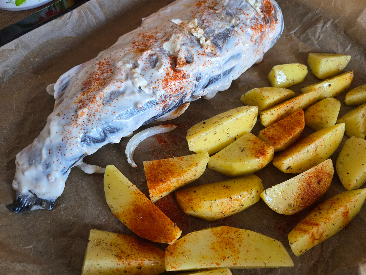 Рыба была с головой, внутри оказались молоки, которые с удовольствием съел Иннокентий. Сделала надрезы, вложила в них тонкие полосочки сливочного масла, натёрла специями и сметаной. Внутрь положила стебли укропа, под рыбку репчатый лук. Картошку посолила, добавила специй и растительного масла.