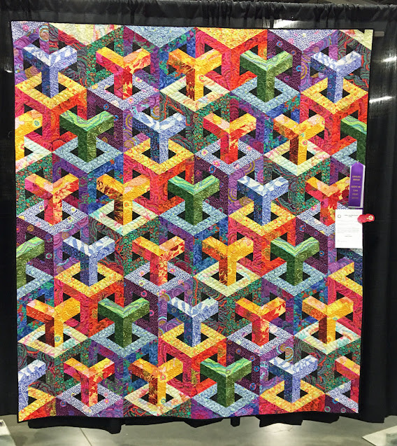 На изображении представлено лоскутное одеяло с узором Escher Cubed (Кубы Эшера). 
Узор создает оптическую иллюзию трехмерных кубов. 
Одеяло было изготовлено Кристи Хоффман и названо «Kaffe and Tula Meet Escher Cubed». 
Для создания узора использовался шаблон, разработанный Кристофером Вайнхолдом. 
При пошиве не использовались Y-образные швы, что упрощает процесс, несмотря на сложный вид дизайна. 
