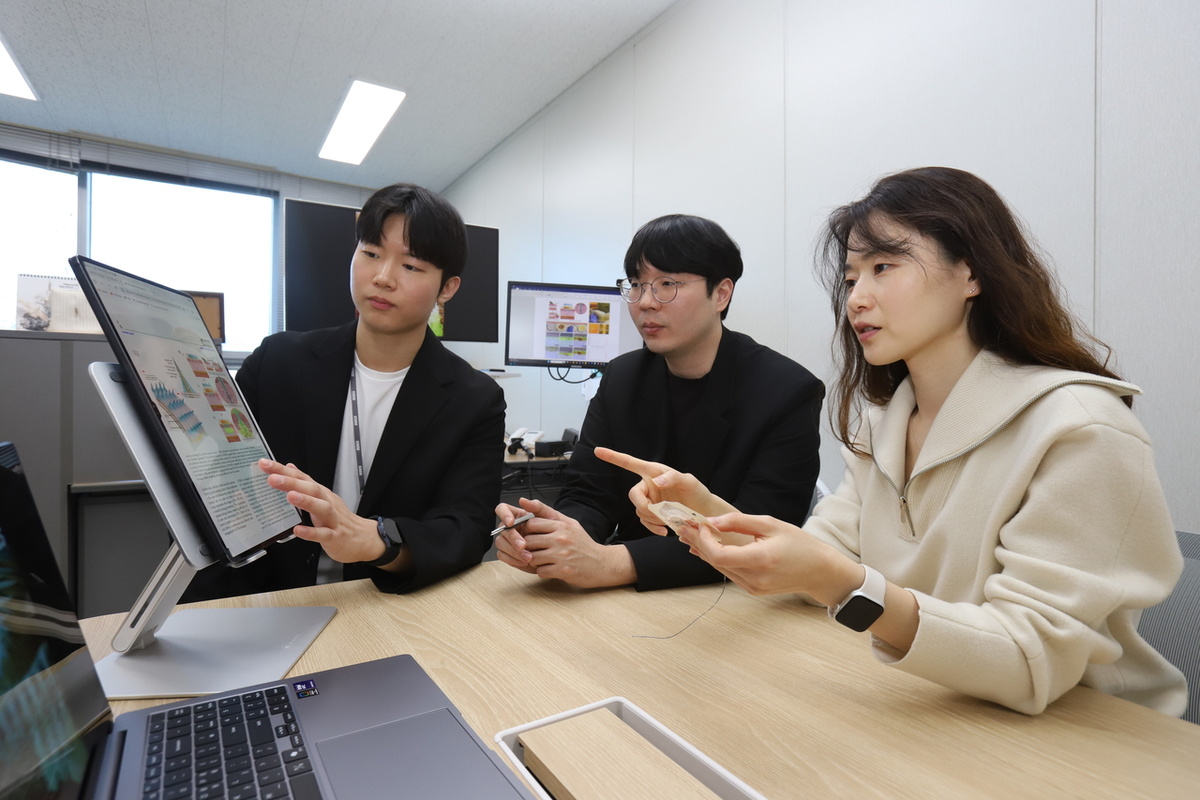 Чон Со Хи (справа), главный исследователь Корейского института машиностроения и материалов, обсуждает со своей исследовательской группой, изучая образец микроиглы [Предоставлено Корейским институтом машиностроения и материалов]