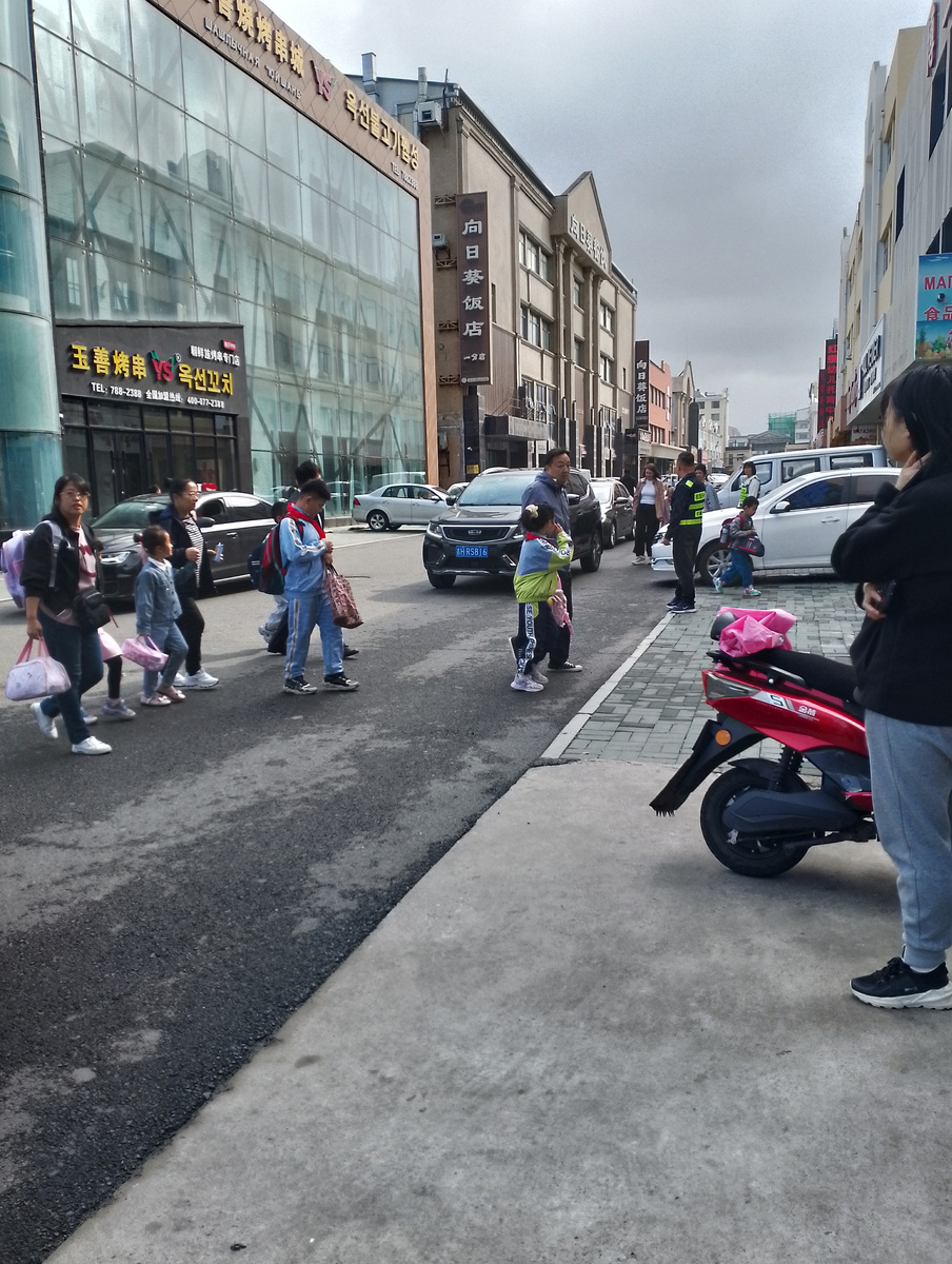 Родители высаживают из машин детей.Дядечка в жилете помогает,а потенциальных прогульщиков заворачивает во двор.