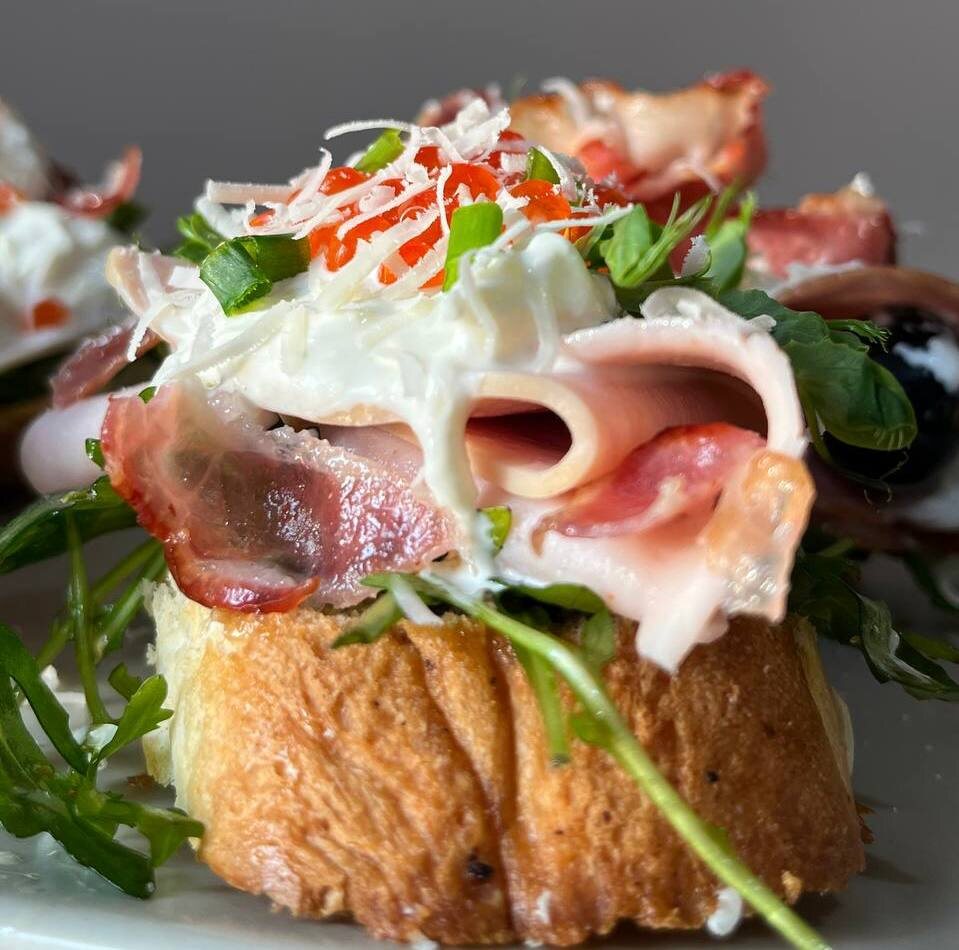 Брускетта с ветчиной индейки, беконом, рукколой, стрчателлой и икрой.