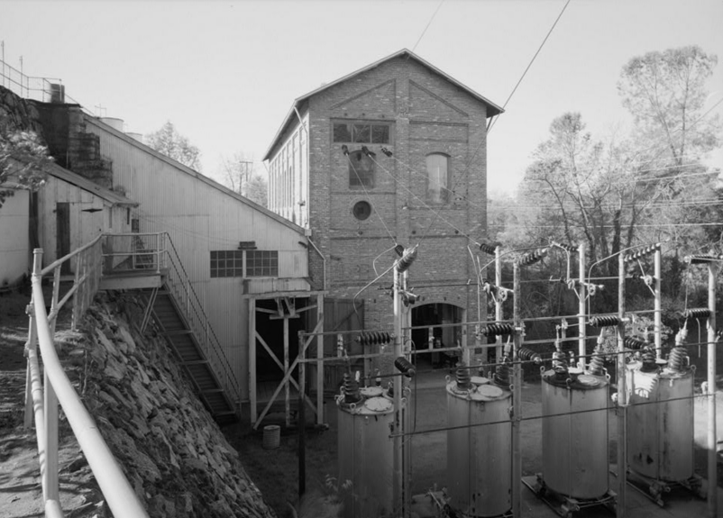 Здание машинного зала станции, деревянный пристрой слева закрывает подающий трубопровод к гидроагрегатам.