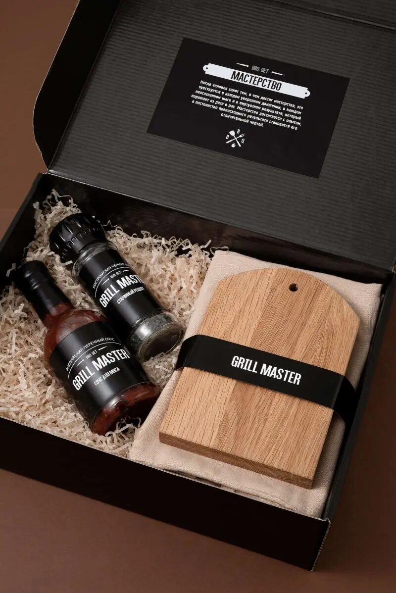 Подарочный набор от "Атрибутики" #333 Грильмастер: Доска из натурального дерева для сервировки , Коробка крафтовая черного цвета с наклейкой (брендируется наклейка) , Соус перечный. 230г. в манжете (брендируется манжета) , Фартук из 100% переработанного хлопка , Черная соль в мельнице. 110 г в манжете (брендируется манжета)