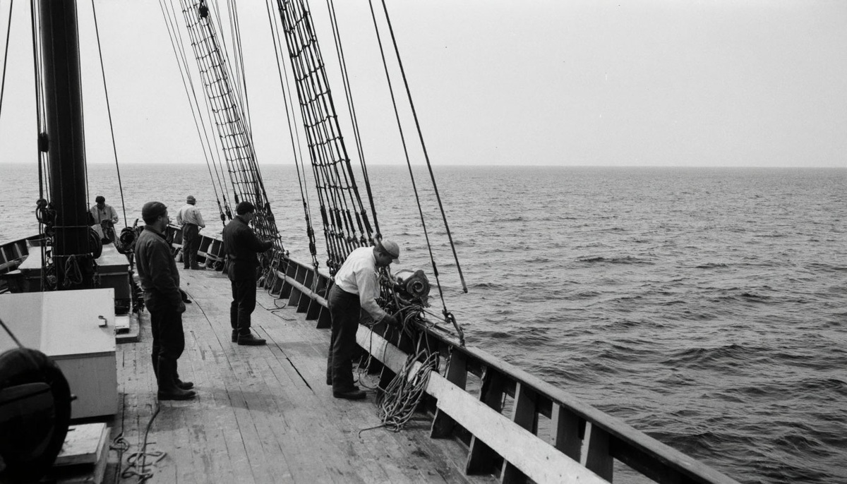 архивное фото 1920‑х годов — исследовательское судно на фоне бескрайнего океана. На палубе — учёные с приборами для замеров, рядом — поднятый из глубин трал с неизвестными морскими существами.Подпись: «Начало эпохи океанографии: когда человечество впервые заглянуло в бездну».
