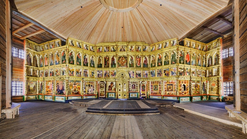  В кадре — 22 дерева-колонны, поддерживающие купола без единого гвоздя. Свет проникает через узкие окна, создавая божественные лучи, освещающие иконостас работы мастеров XVIII века. Координаты: 62°04′15″ с.ш. 35°12′30″ в.д. Высота церкви — 37 метров. Возраст сооружения — 315 лет (построена в 1714 году). Температура внутри +18°C, влажность 65%. На стенах видны следы времени — потемневшее дерево с уникальной текстурой.