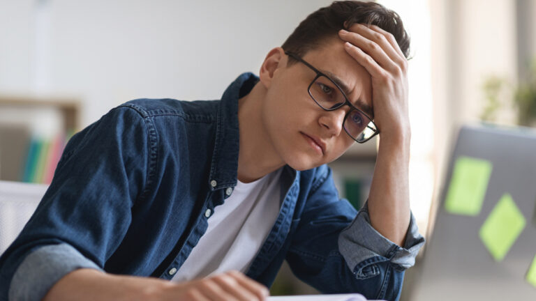    Job Burnout. Depressed Young Manager Looking At Laptop Screen While Working In Office, Tired Male Employee Suffering Lack Of Ideas And Deadline Stress, Having Problems With Creativity, Closeup